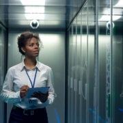 Image of a person walking through a data center with a laptop.