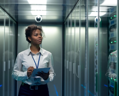Image of a person walking through a data center with a laptop.