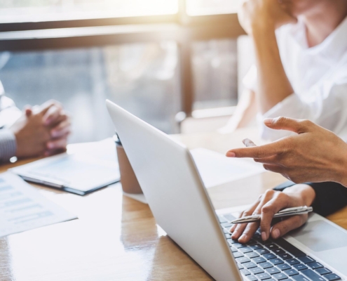 Image of business people discussing in a meeting while using a laptop.