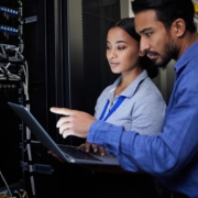 Image of two people looking at a computer connected in a data center.