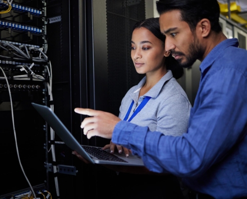 Image of two people looking at a computer connected in a data center.